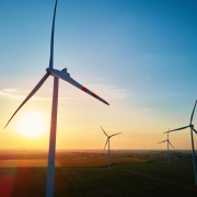 Silhouetted wind turbines in countryside landscape during sunset